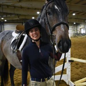 woman standing with horse in an arena